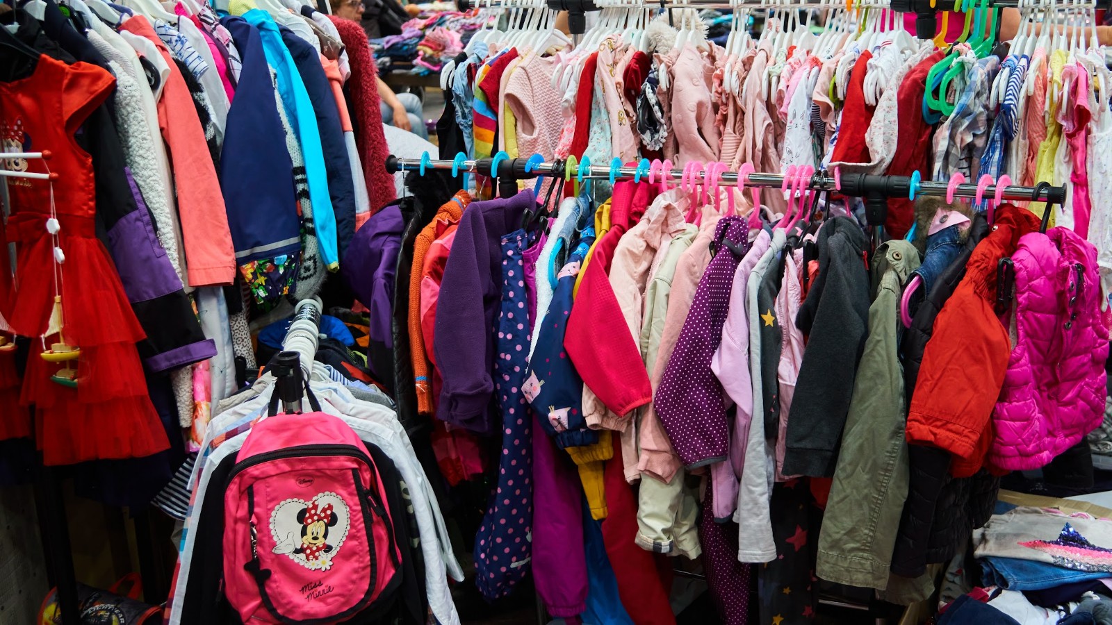 piccolino*-Kinderflohmarkt, bunte Kinderbekleidung hängt auf einem Garderobenständer