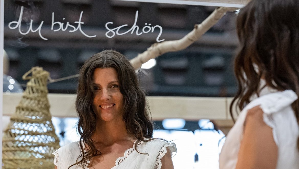Eine Frau blickt in den Spiegel mit der Aufschrift "du bist schön" auf der TrauZeit 2023 der MESSE BREMEN